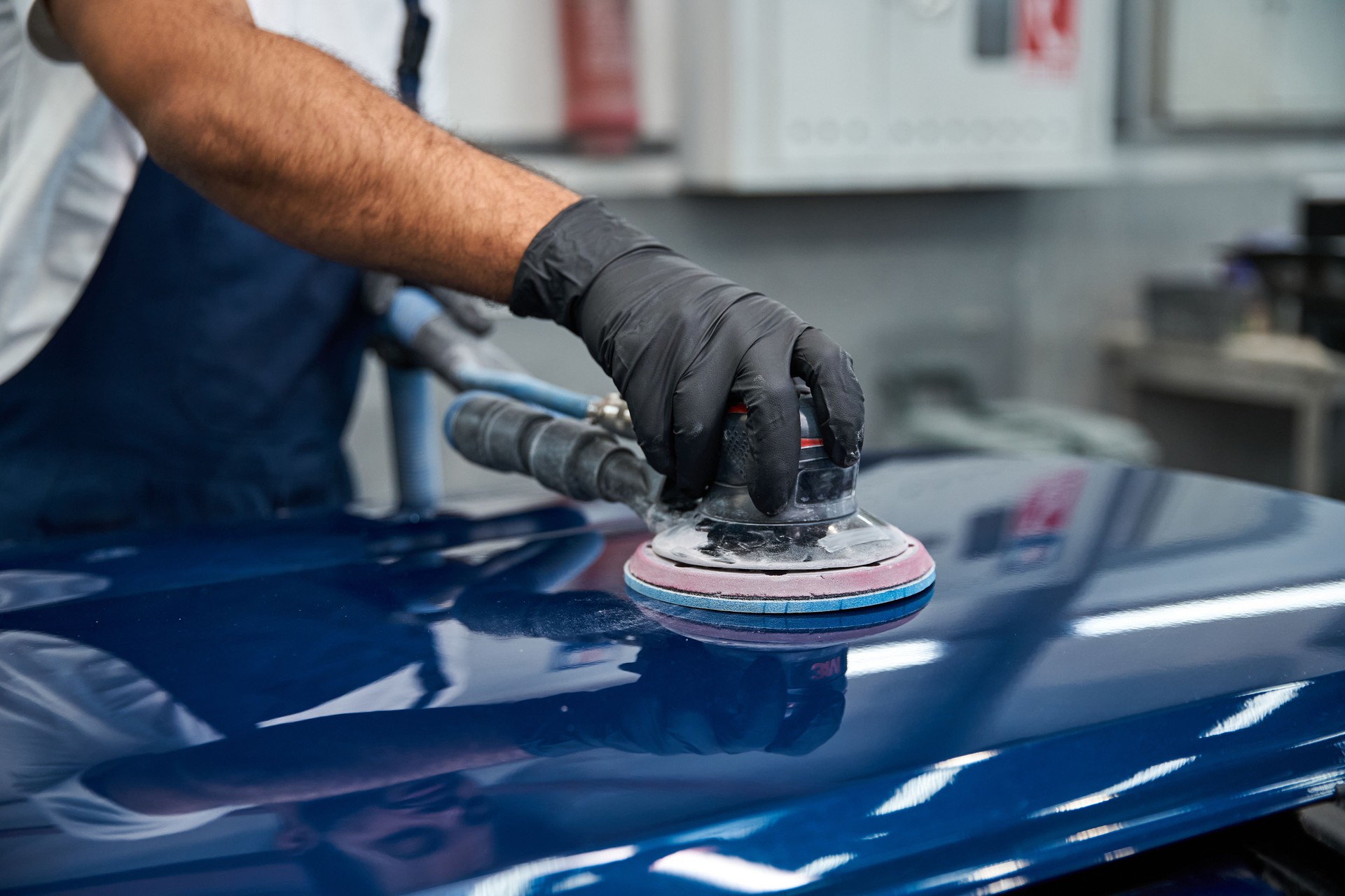 Young mechanic expertly polishing car surface in modern repair shop